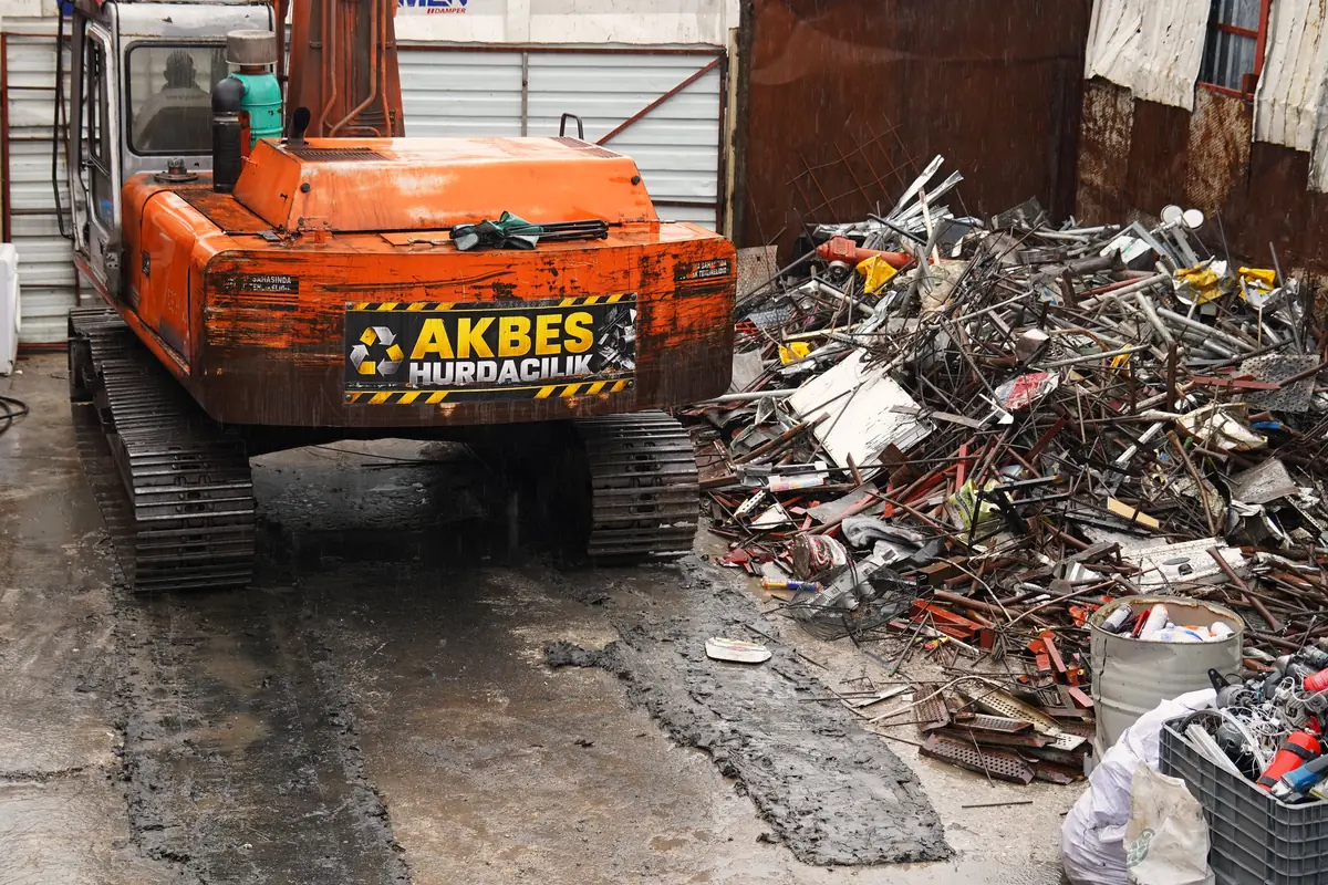 Sahada ayrılmış metal hurda yığını ve AKBES ekskavatörü